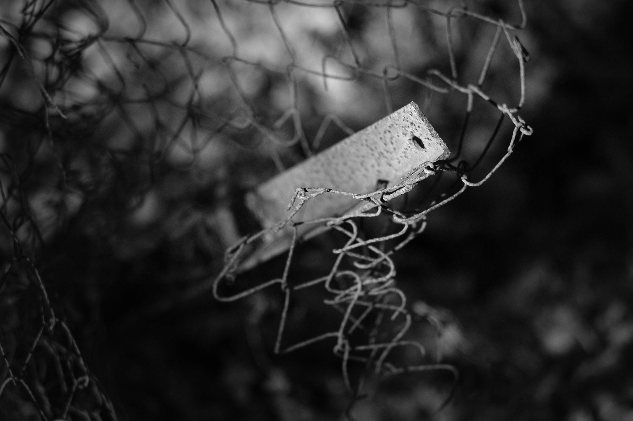 tangle of derelict chain-link fencing with metal post, in black and white