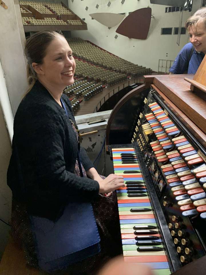 Woman sat at the Light Console, with view of auditorium behind