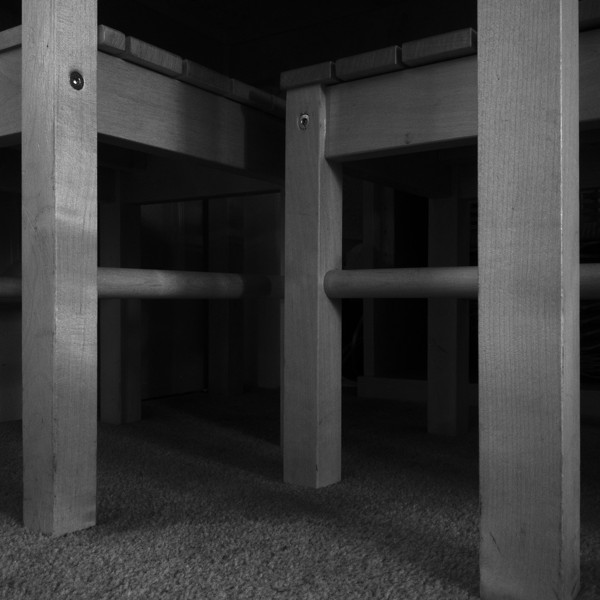 close up of the legs of two chairs under a table, dramatically lit